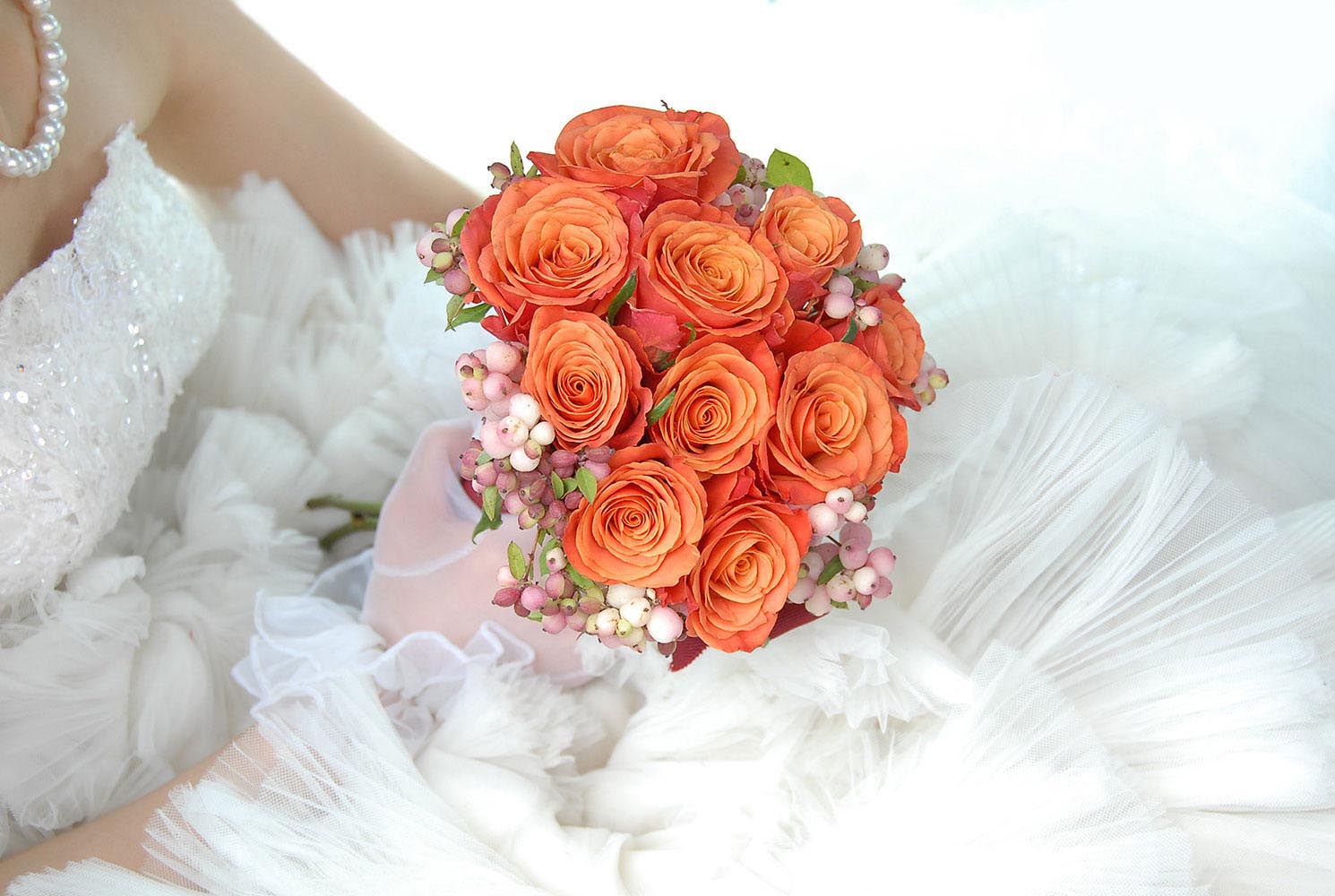 Bouquet de mariage orange tenue par la mariee sur sa robe