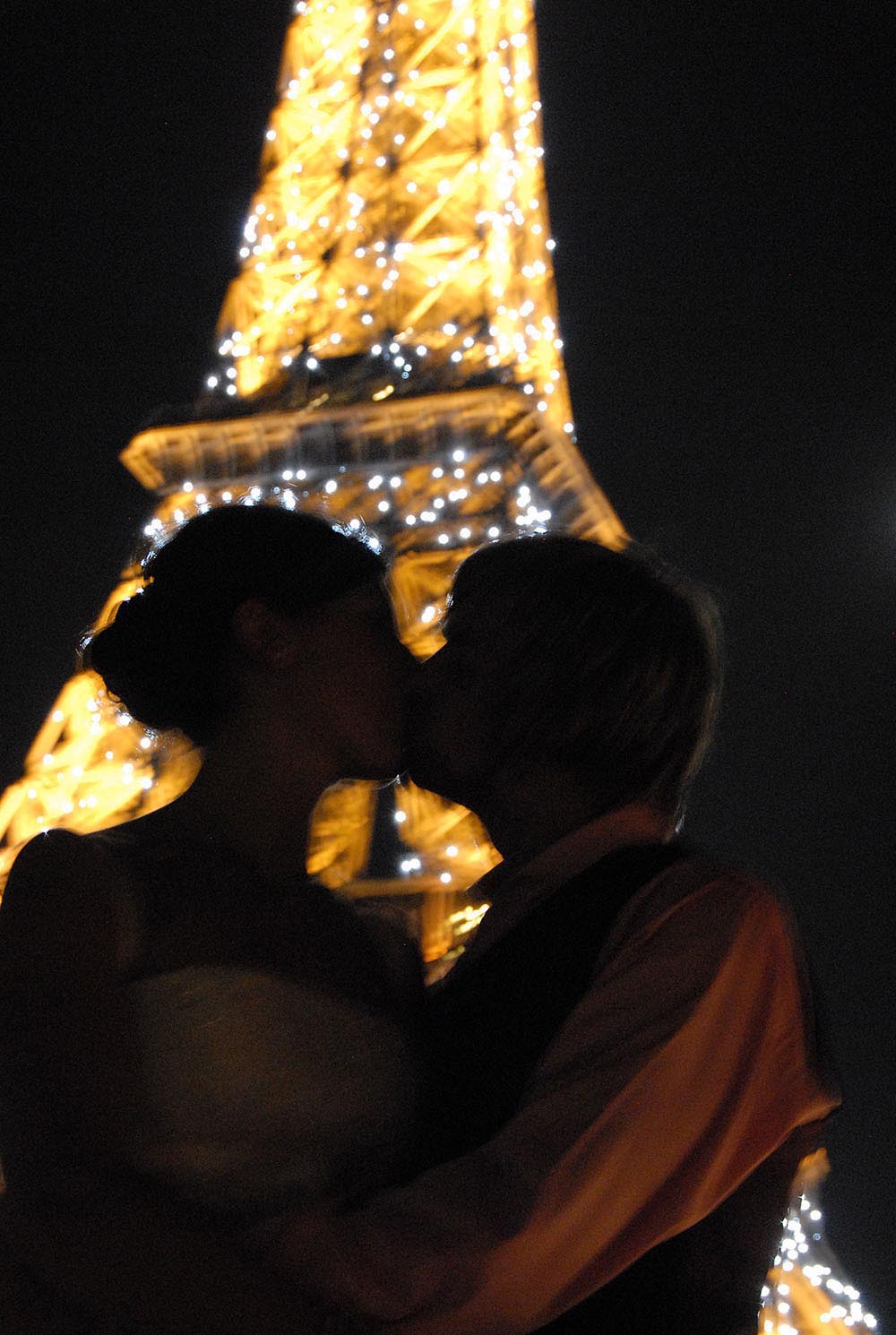 Couple de maries s'embrassant avec la Tour Eiffel illumine de nuit