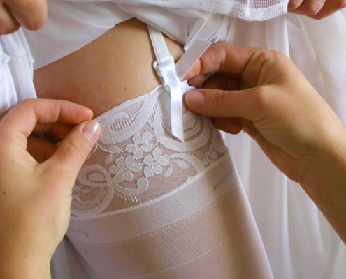 Bride getting her stockings adjusted for the wedding